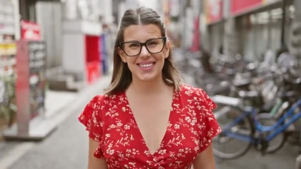 Mujer hispana alegre parpadeando una sonrisa ganadora en las calles osaka - Imágenes, Vídeo