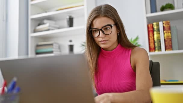 Kendine güveni tam genç İspanyol bir kadın, zarif bir kıyafet giymiş, ofisteki bilgisayarında çalışırken sevinçle ışıldıyor, profesyonel bir başarı sergiliyor. - Video, Çekim