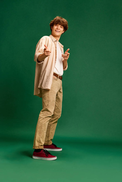 Full-length portrait of young successful, motivated man points to camera and say that you can do everything against green studio background. Concept of human emotions, facial expression, business. Ad - Фото, изображение