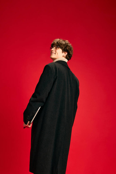 Young executive. Back view of modern officially dressed young man, student go to university or work against red studio background. Concept of human emotions, beauty, fashion and style, study, business - Photo, Image