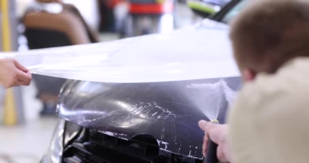 Master reparateur wikkeling kap van de auto met beschermende plastic film 4k film slow motion. Detailservice voor auto 's - Video