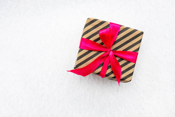 Joululahja laatikko joulun symbolina valkoisella lumella taustalla, konsepti uudelle vuodelle. - Valokuva, kuva