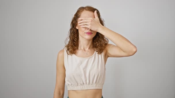 Shocked young woman peeking through fingers, a timid expression covering her face. standing, wow-eyed, embarrassed against isolated white background. - Footage, Video