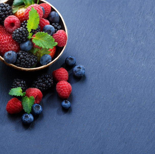 Assorted fresh garden berries on a black background, space for t - Фото, зображення