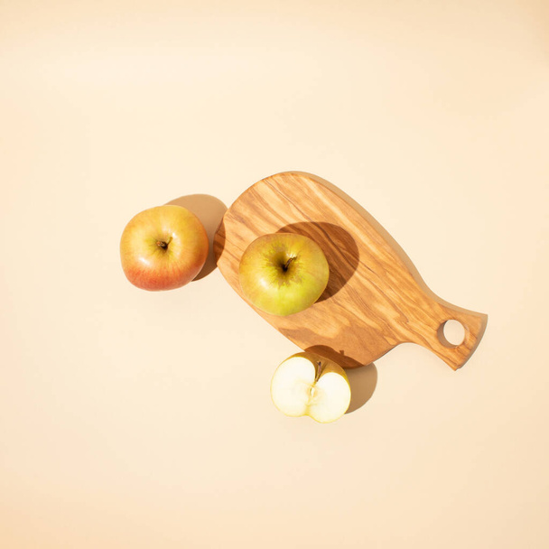 Placa de madeira com maçãs frescas em um fundo bege claro. Depósito plano. - Foto, Imagem