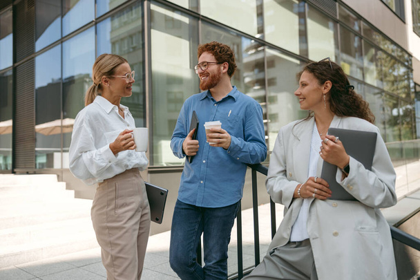 Fröhliche Geschäftsleute reden und lachen in der Pause außerhalb des Büros - Foto, Bild