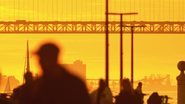 Ένας άντρας στέκεται μπροστά σε μια γέφυρα το ηλιοβασίλεμα. - Πλάνα, βίντεο