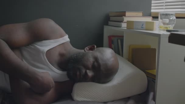 Hombre afroamericano despertando por la mañana en casa, estirándose, luego tocando su nueva almohada ortopédica y sonriendo - Imágenes, Vídeo