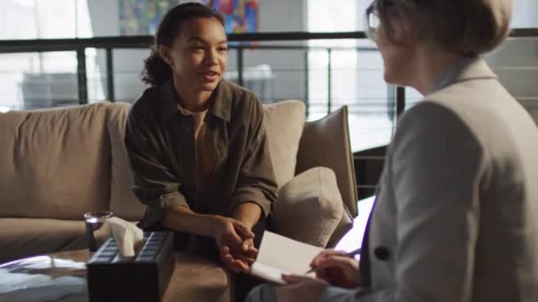 Přes rameno záběr mladé biracial žena v kanceláři psychologů mluví radostně s její psycholog - Záběry, video