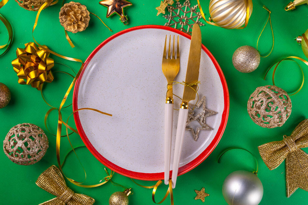 Χριστουγεννιάτικο και Πρωτοχρονιάτικο τραπέζι ρύθμιση φόντο ευχετήρια κάρτα, εορταστική πρόσκληση γεύμα ή μενού. Επίπεδη lay με πιάτο, μαχαιροπήρουνα που, με χριστουγεννιάτικες διακοσμήσεις, top view αντίγραφο χώρου - Φωτογραφία, εικόνα