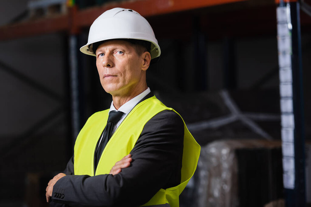 confident man in safety vest and hard hat standing with arms crossed, professional headshot - Photo, Image