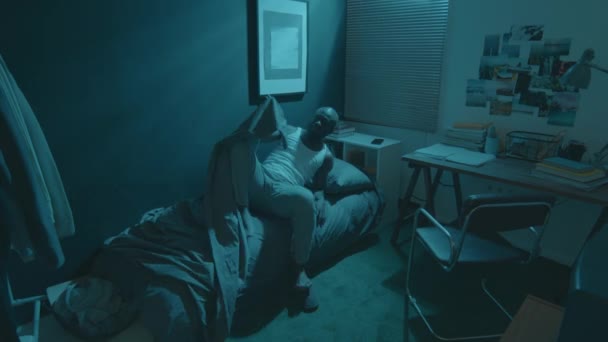 Zeitraffer eines Afroamerikaners, der nachts zu Hause an Schlaflosigkeit leidet. Er wechselt die Seiten, zieht die Decke aus und sitzt auf dem Bett, während er versucht einzuschlafen - Filmmaterial, Video
