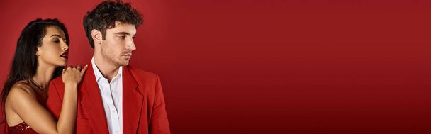brunetka młoda kobieta z czerwonymi ustami uwodzi przystojny mężczyzna w formalnym stroju na czerwonym tle, baner - Zdjęcie, obraz