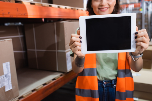 空白のスクリーンが付いているデジタル タブレットを握る安全ベストの作られ,幸せな女性の倉庫の労働者 - 写真・画像