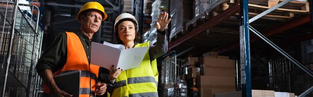 warehouse workers banner, woman with folder showing direction to middle aged colleague - Photo, Image