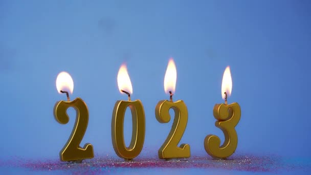 Fond de vacances Bonne année avec nombre de bougies lumineuses dorées pour le Nouvel An 2023. Nombres de l'année 2023 fabriqués par des bougies brûlantes d'or sur fond bleu.  - Séquence, vidéo