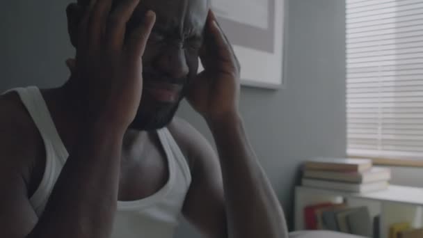 Afro-americano com distúrbio do sono esfregando suas têmporas enquanto sente dor de cabeça e fadiga depois de acordar de manhã em casa - Filmagem, Vídeo
