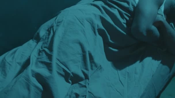 Top alas näkymä Afrikkalainen amerikkalainen mies peitetty huopa nukkuu hänen sängyssä kotona yöllä - Materiaali, video