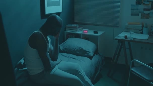 眠れないアフリカ系アメリカ人の男がベッドに座って不眠症に苦しみ,彼の顔をこすり,自宅で夜間に疲れを感じる - 映像、動画