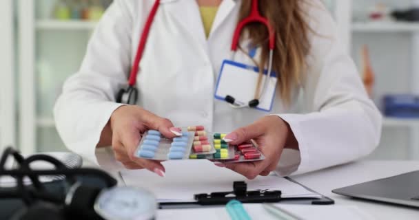 Γυναίκα γιατρός κατέχει στο χέρι συσκευασία των διαφόρων φουσκάλες με χάπια στην κλινική. Επιλογή ποιοτικών φαρμάκων - Πλάνα, βίντεο