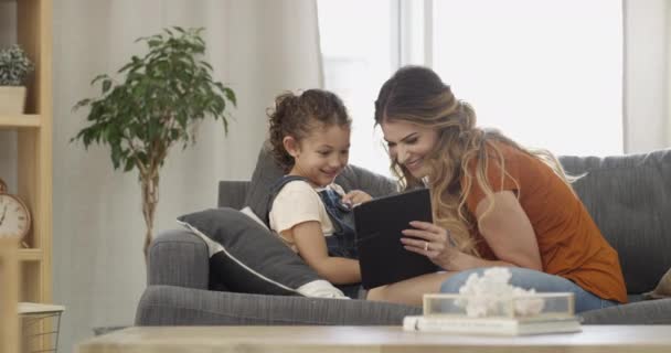 Mother, child and tablet on couch, streaming series and cartoon movie or mobile app. Mom, daughter and digital technology on sofa, social media and funny joke or online humor, conversation and chat. - Footage, Video