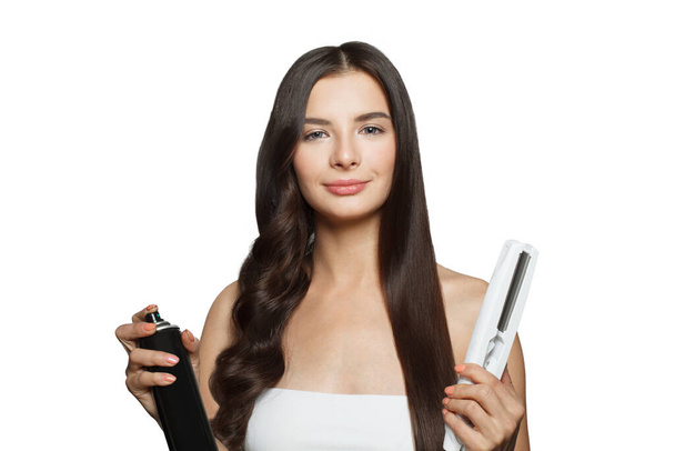 Hübsche junge erwachsene Frau mit Haarbügeleisen und glätten ihre langen braunen Haare auf weißem Hintergrund, Studio-Mode Schönheitsporträt. Haarbügel- und Friseurkonzept - Foto, Bild