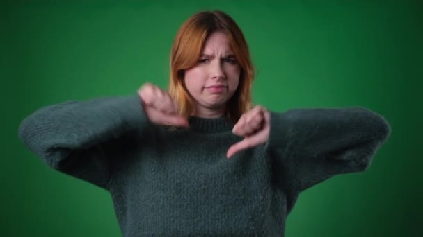Red haired Caucasian woman, dressed casually, expresses a negative sentiment by giving thumbs down. Her expressions of dissatisfaction and the downward gesture convey a sense of disagreement. - Footage, Video