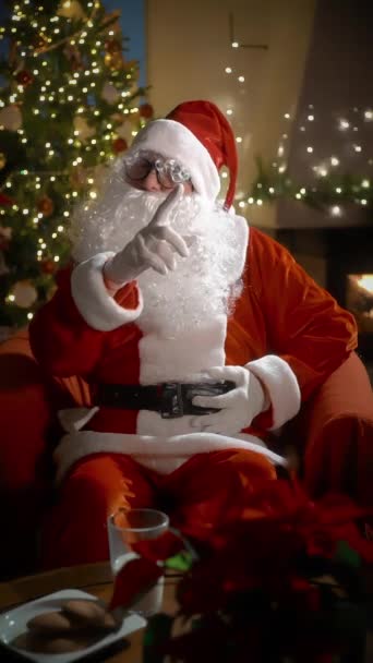 Webcam view Santa Claus wishing Merry Christmas and Happy New Year to children and adults online video calling, holding gifts in his hands in virtual video online chat sitting in his residence on Xmas - Imágenes, Vídeo