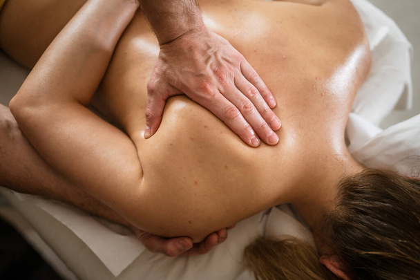 Невідома жінка лежить, маючи масаж спини та шиї чоловічим кавказьким терапевтом у салоні косметичних процедур Концепція релаксації охорони здоров'я Копіювати простір
 - Фото, зображення