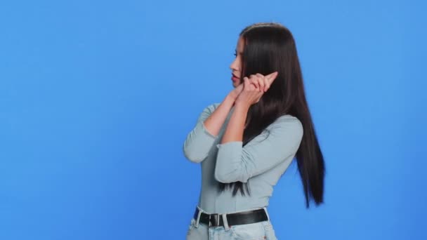 Caucasian young woman pointing around with finger gun gesture, looking confident, making choice shooting killing with hand pistol right on target. Girl isolated alone on blue background. Advertisement - Footage, Video