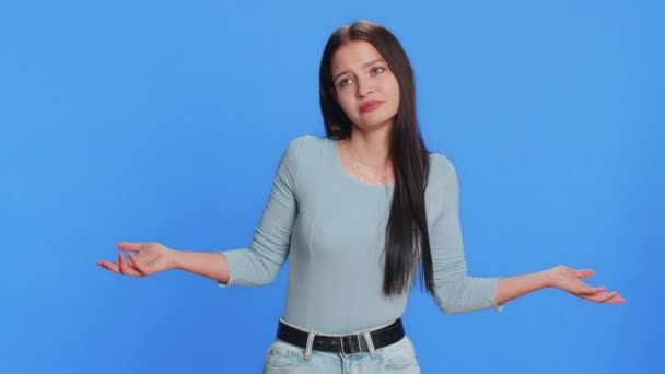 I dont know what to say. Confused Caucasian young woman feeling embarrassed about ambiguous question, having doubts, no answer, idea, being clueless, uncertain. Teen girl isolated on blue background - Footage, Video