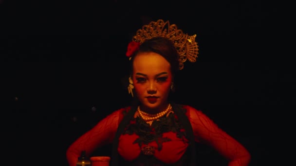 una mujer asiática está sentada frente a las ofrendas rituales con una expresión astuta y aterradora por la noche - Imágenes, Vídeo