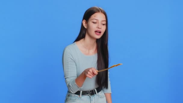Magician witch young woman gesturing with magic wand fairy stick, making wish come true, casting magician spell, advertising holidays sale discount. Pretty girl isolated on blue studio background - Footage, Video