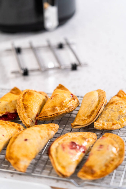 Empanadas de cerises douces fraîchement cuites dans la friteuse sur le comptoir de la cuisine. - Photo, image
