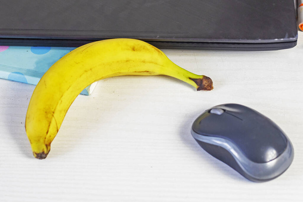 банан на рабочем столе возле компьютерной мыши и ноутбука. Нарботские закуски и идеи - Фото, изображение