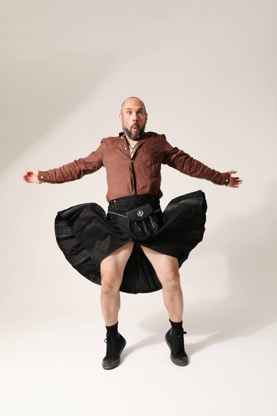 Happy rock musician. A man with shaved head wearing kilt posing indoor. Vertical. High quality photo. - Valokuva, kuva
