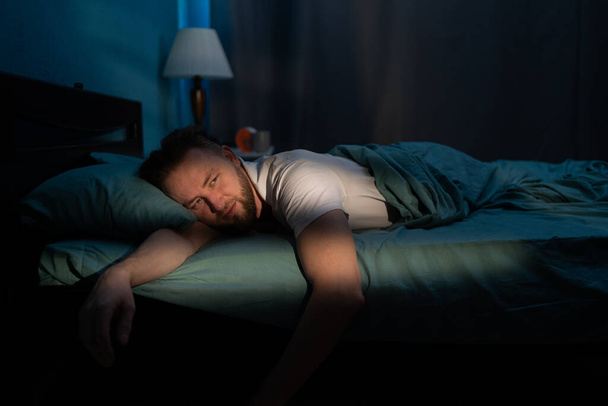 Uneton valkoihoinen mies makaa sängyssä ja kärsii unettomuudesta. Ihmiset, nukkumaanmenoa ja lepoa koskeva käsite - Valokuva, kuva