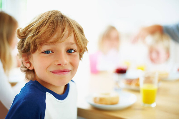 Kid, ontbijt en portret thuis in de ochtend met eten, glimlachen en blij van het eten. Familie, eettafel en hongerig jong kind met maaltijd voor gezondheid en voeding in een huis met sap. - Foto, afbeelding