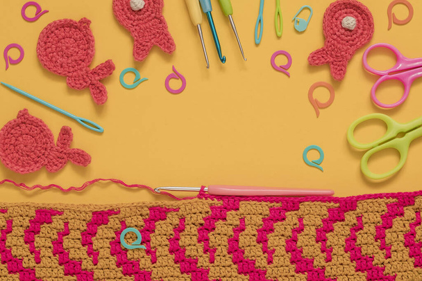 Kreatywne tło z tkaniny na szydełku, narzędzia na szydełku i króliczki na drutach na żółtym tle. Widok góry. Przestrzeń kopiowania, - Zdjęcie, obraz