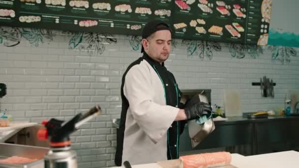 Primer plano del chef de sushi con quemador de gas en rollos de salmón fritos a mano antes de servir en el restaurante de sushi - Metraje, vídeo
