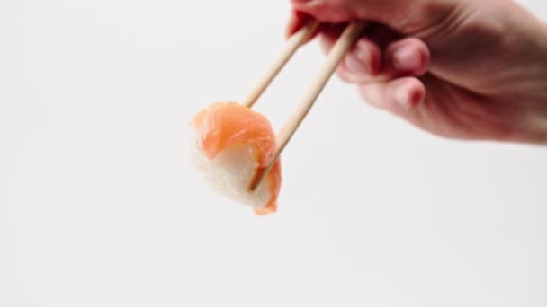 Крупный план мужской руки с палочками для еды, держащими креветки суши нигири в воздухе на белом фоне - Кадры, видео