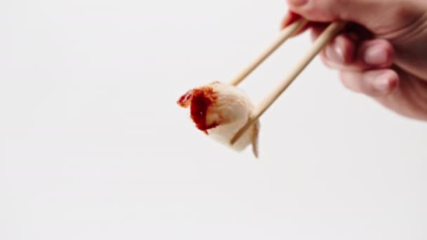 Крупный план мужской руки с палочками для еды, держащими один угорь суши в воздухе на белом фоне - Кадры, видео