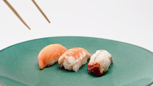 Крупный план мужских рук с палочками для еды, держащими суши из угря и суши из лосося на белом фоне - Кадры, видео