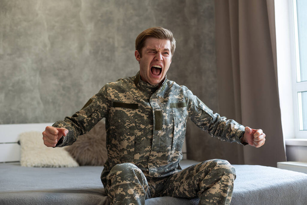 Jeune homme caucasien portant l'uniforme de l'armée de camouflage en colère et furieux. - Photo, image