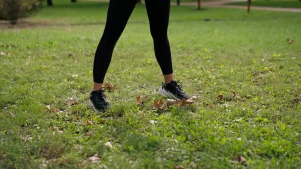 close-up Een sportmeisje tijdens de ochtendtraining in frisse lucht maakt cirkelvormige bewegingen met haar bekken dat haar heupgewricht en onderrug uitrekt - Video