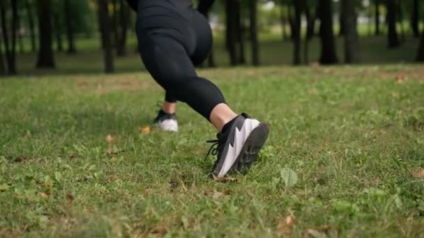 Junges Mädchen in Sportbekleidung bei Ausfallgymnastik, um das Gleichgewicht zu trainieren und die Oberschenkelmuskulatur zu dehnen - Filmmaterial, Video