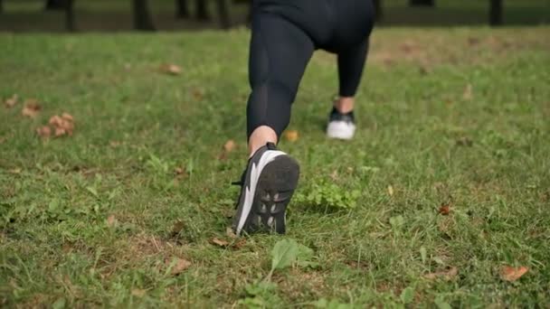 Nahaufnahme der Beine eines jungen Mädchens in Sportbekleidung, die Ausfallbewegungen macht, trainiert das Gleichgewicht und dehnt die Oberschenkelmuskulatur Rückansicht - Filmmaterial, Video