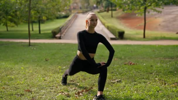 Mladá dívka ve sportovním oblečení dělat výpad cvičení vlak rovnováhu a protáhnout stehno a nohy svaly - Záběry, video