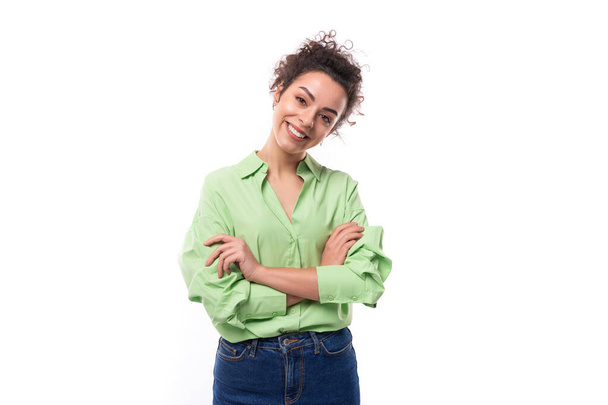 молода позитивна весела струнка європейська брюнетка кучерява жінка з зачіскою з хвостом одягнена в зелену сорочку, посміхаючись на білому тлі з місцем для тексту. - Фото, зображення