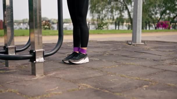 Közelkép Lábak a lány sportedző elvégzése gyakorlatokat rugalmas szalag erősítése izmok sportpályán - Felvétel, videó